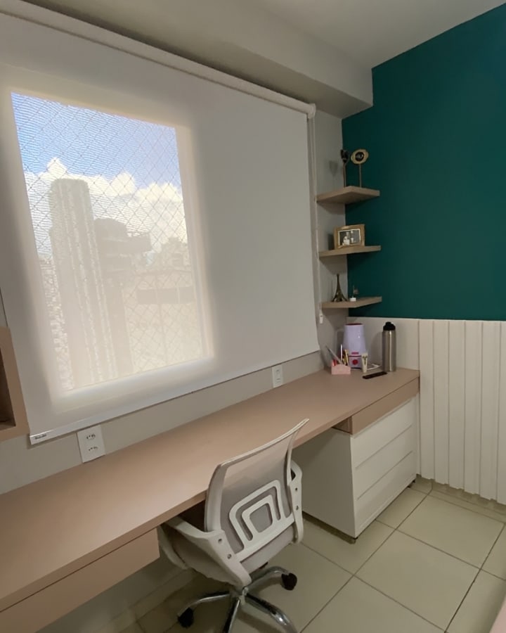 Home office com persiana rolô clara sobre bancada de trabalho, em Goiânia