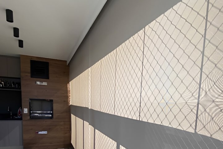 Varanda com persianas rolô ao longo de toda a extensão, em apartamento de Goiânia
