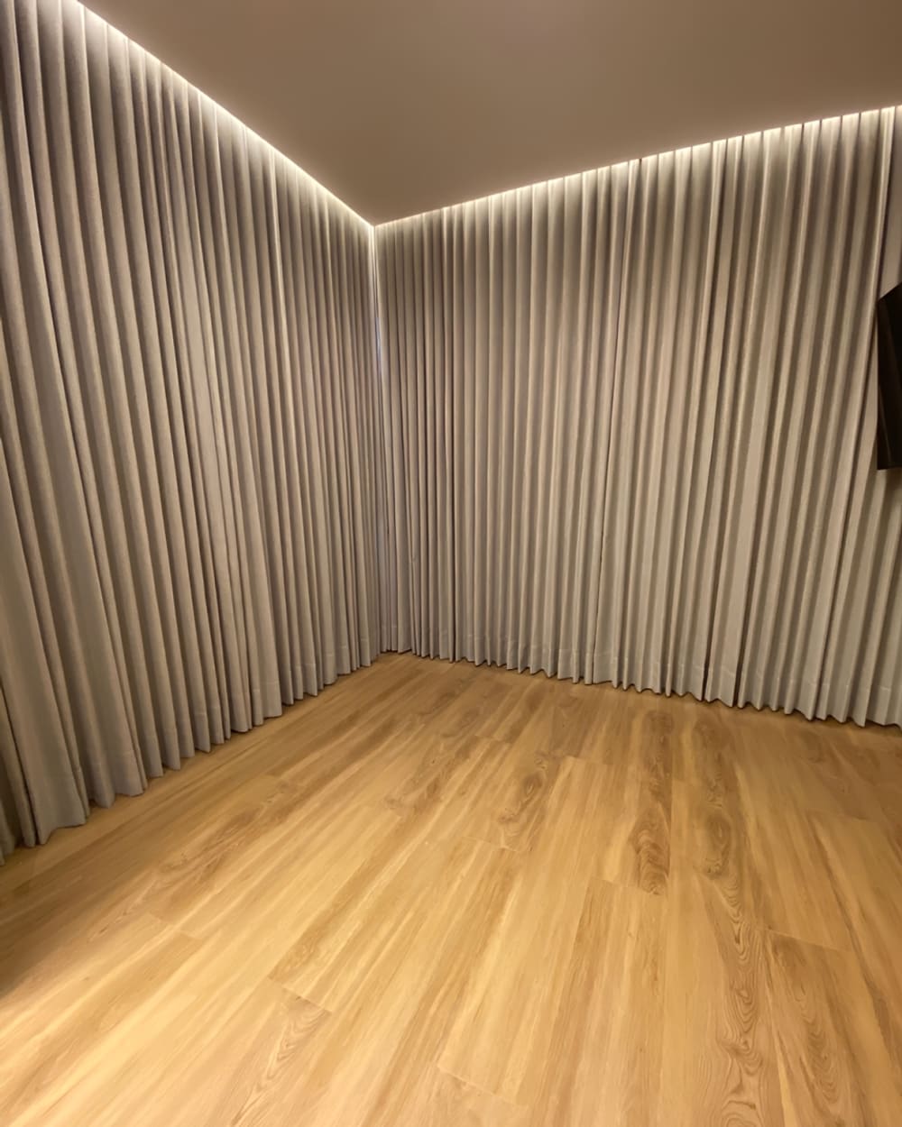 Quarto com cortina sob medida em duas paredes e piso de madeira, em Goiânia