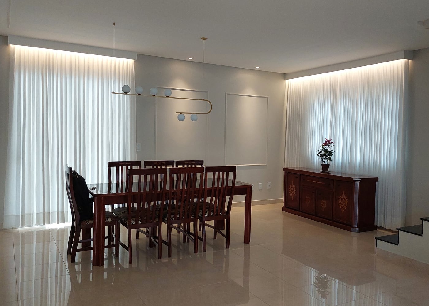 Sala de jantar em Goiânia com cortinas de voil sob medida do teto ao chão em duas paredes, com iluminação de sanca